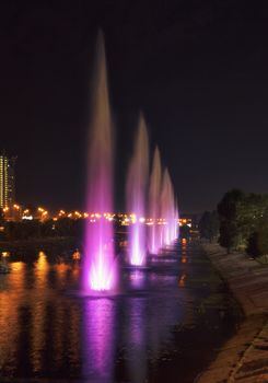A beautiful, bright and high fountains on the Rusanovskaya channel of the Dnipro embankment of the cityscape in the night Kyiv