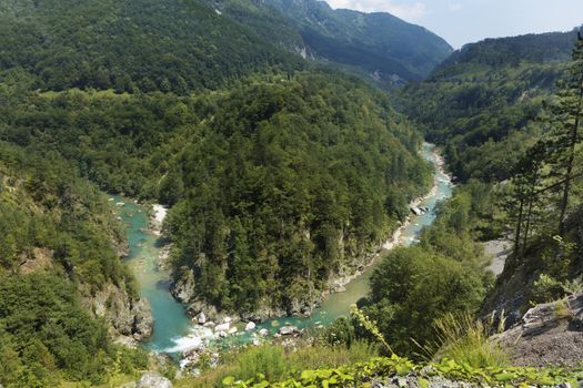 The pure turquoise water of the mountain river overcomes the stone rapids in the national park of central Montenegro. Ecology concept.