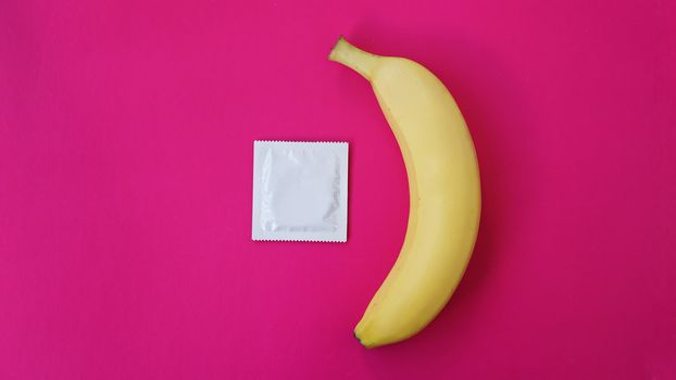 Condom and banana on pink background. Concept of sex and erectile dysfunction.