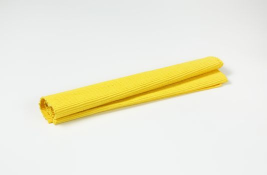 Folded yellow woven cotton place mat