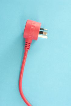 Red integrated electric cable with a three prong Australian plug lying on a blue background with copy space in a power and energy concept