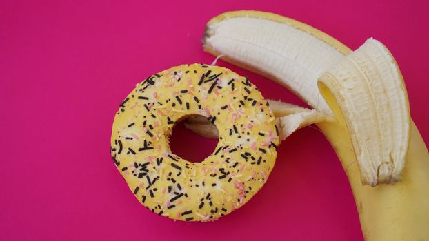 Sweet donut and banana on pink color background. Sex and Erotic concept. Banana hugs donut
