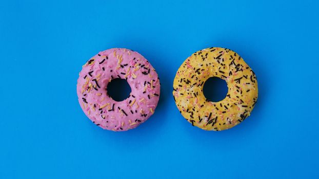 Two fashion round donuts on blue color. colorful minimalism concept.