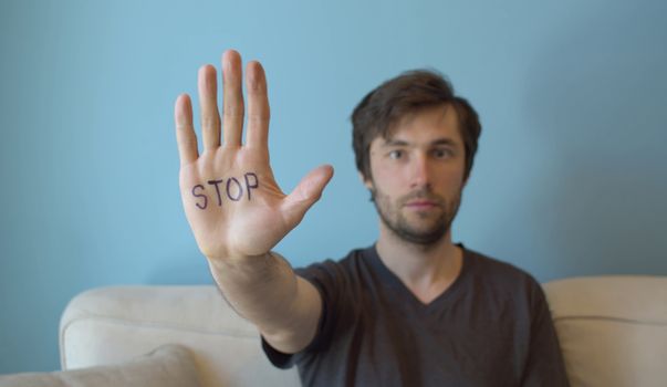 Young man showing stop sign on the hand. Movement against sexual harassment.