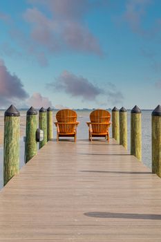 Adirondack chairs on a wooden pier in the tropics