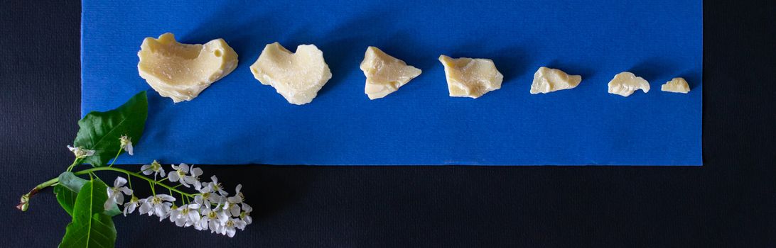 Pieces of chocolate are laid out on a blue background. Ingredients for making healthy and delicious sugar-free sweets at home. Top view, close-up.