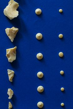 Pieces of chocolate are laid out on a blue background. Ingredients for making healthy and delicious sugar-free sweets at home. Top view, close-up.