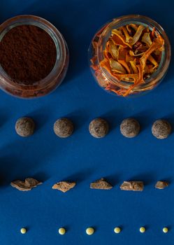 Dark and white chocolate, cocoa and candied orange are laid out on a blue background. Ingredients for making healthy and delicious sugar-free sweets at home. Top view, close-up.