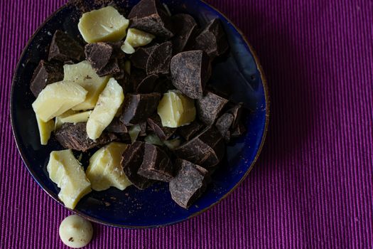 Broken pieces of dark bitter chocolate and white milk chocolate. Ingredients for home cooking of healthy sweets without sugar.