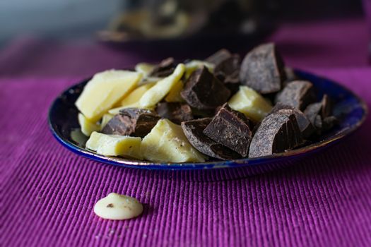 Broken pieces of dark bitter chocolate and white milk chocolate. Ingredients for home cooking of healthy sweets without sugar.