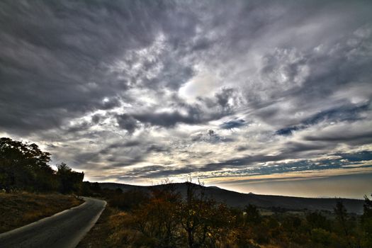 Long straight road with dramatic clouds