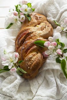 Fresh baked sweet braided yeast bun, wicker russian loaf with spring flowers, vertical image