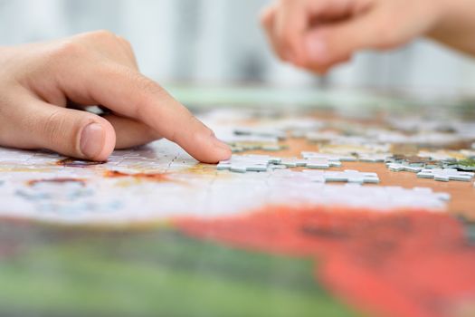 Close-up of children's hands collecting jigsaw puzzles