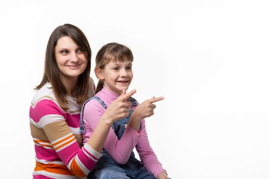 Girl sitting on moms lap and joyfully point a finger to an empty place