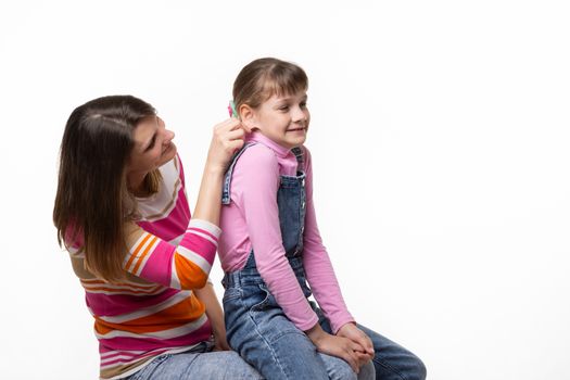 Girl sitting on moms lap, mom fun tugs at the girls ear