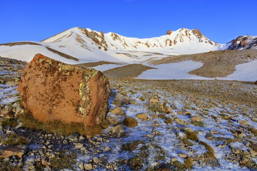 A large boulder in defocus on the picturesque path to the top of Mount Erciyes on a clear sunny day against a blue clear sky in central Anatolia, Turkey.