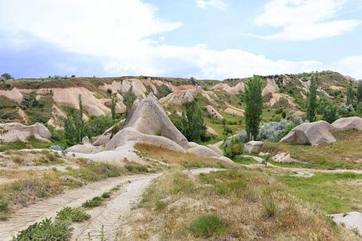 Dirt road leading through the landscape of ancient canyons and abandoned caves of Cappadocia