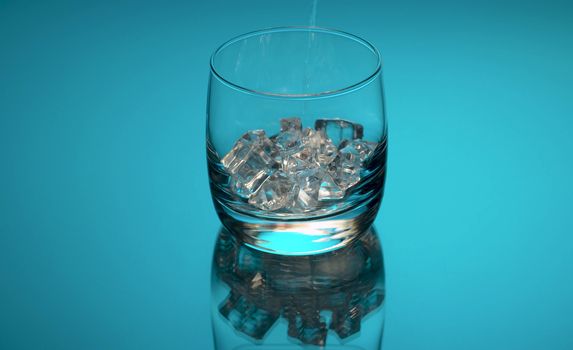 Close up tonic, soda sparkling water pouring into a glass with ice on a blue background. Refreshing mineral water.