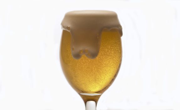 Close up of beer's foam rising in a glass, side view, white background. The foamy drink overflows and spills onto the table.