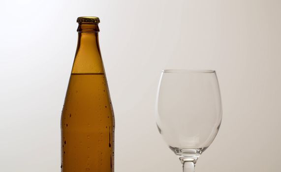 Close up misted bottle of cold beer on the table. White background. Drops of water flowing down. Craft beer closeup