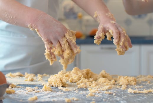 Close up child's hands in the dough. Kid cooking pastry in bright kitchen.