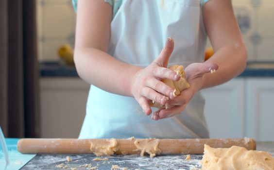 Close up child's hands knead the dough. Girl cooking pastries in the kitchen