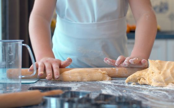 Close up hands of young chef rolling dough. Girl cooking pastries in the kitchen