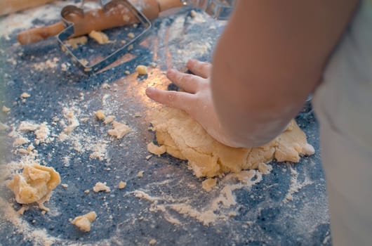 Close up child's hands knead the dough. Girl cooking pastries in the kitchen