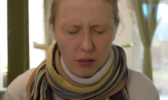 Close up portrait of a woman with flu. She winces and is ready to sneeze