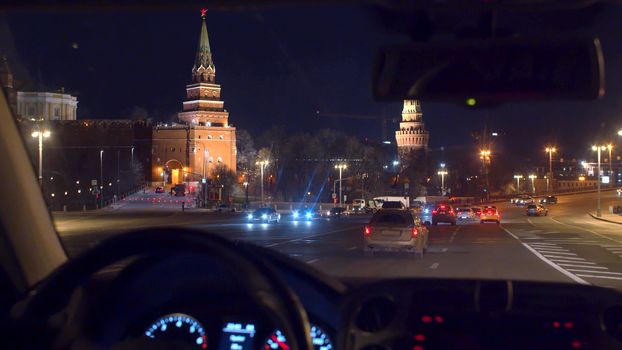 RUSSIA MOSCOW november 2019 - Moscow Kremlin through the windshield at night. Point of view inside moving car. Close up man's hands on the steering wheel and instrument panel lights up.