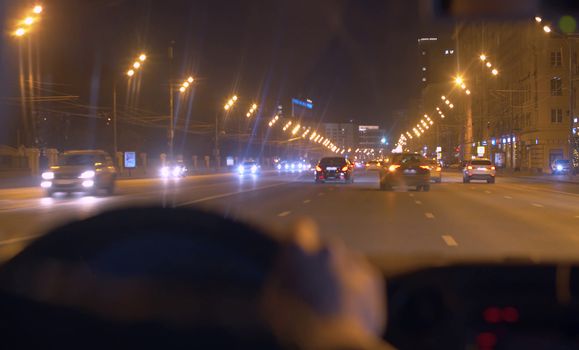 Night city street through the windshield of the moving car. POV.