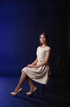 young beautiful girl in light dress sitting on a chair