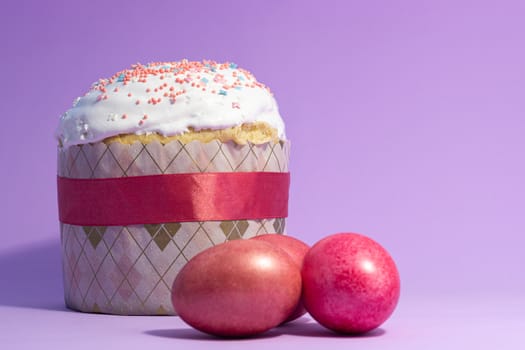 Easter cake decorated with pink decor and rose-colored eggs on a purple background