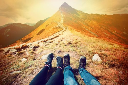 Tourism in mountains. A couple of tourists rest on the mountain path. Nature in mountains at autumn.