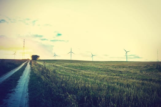 Windmills on the field. Alternative ecological energy. Instagram vintage dark picture.