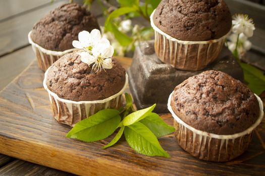 Chocolate maffins with cherry flowers on rustic table
