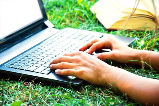 Female hand using a laptop outdoors. Education and technology conceptual image.