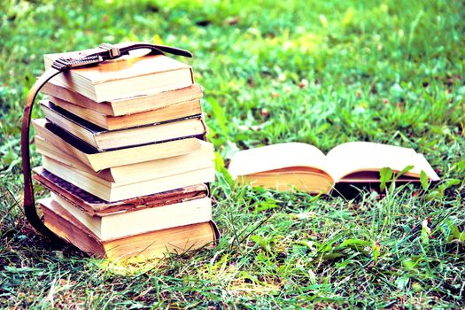 Stack of old vintage books lying on the green grass. Education and back to school concept. Instagram vintage picture.