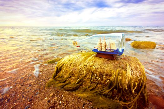 Ship in the bottle lying on the beach. Souvenir conceptual image. Nature in paradise.