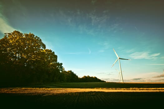 Windmills on the field. Alternative ecological energy. Instagram vintage dark picture.