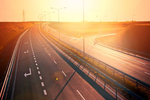 Red sunset over long empty asphalt road highway. Transportation conceptual image.