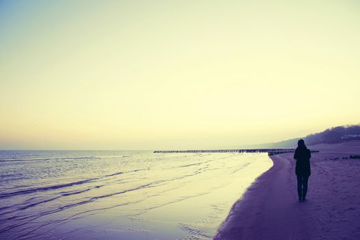 Emotion conceptual image. Lonely woman walking on the beach. Instagram vintage picture.