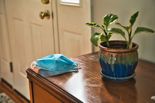 Mask on table looking towards door. Using mask as protecting from coronavirus to flatten the curve