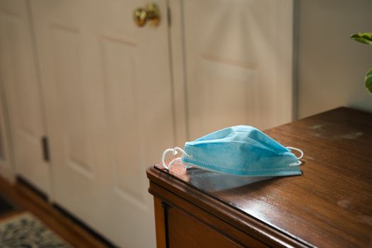 Mask on table looking towards door. Using mask as protecting from coronavirus to flatten the curve