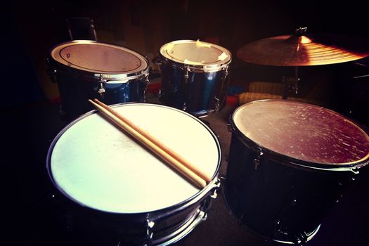 Drums conceptual image. Drums and drumsticks lying on snare drum. Retro vintage instagram picture.