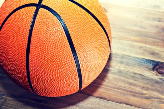 Basketball ball on wooden hardwood floor in the basketball court. Retro vintage picture. Sport concept.