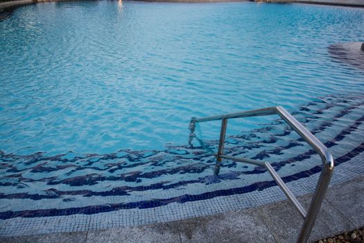 blue swimming pool with teak wood flooring stripes summer vacation