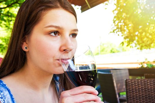 Young attractive women drink glass of red wine in restaurant.