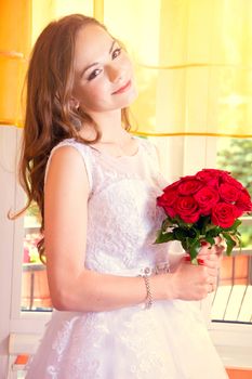 Young beautiful bride in wedding dress with red rose bouquet. Marriage and wedding concept image.