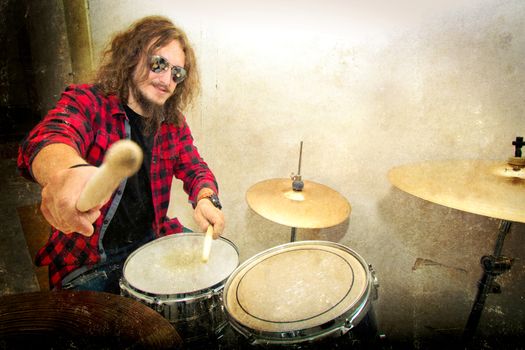 Drums conceptual image. Rock drummer holding drumsticks and playing on drums. Retro vintage grunge picture.